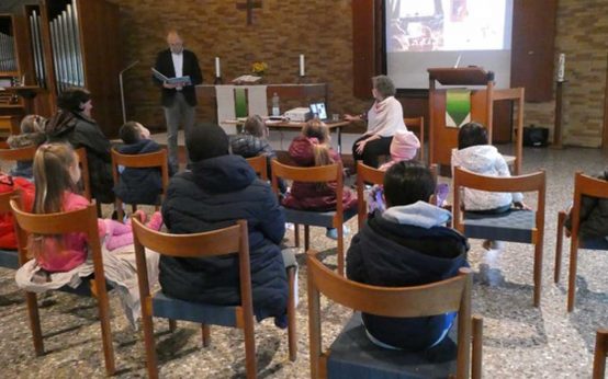 Vorlesetag am Gräselberg: Kinder sitzen in der Lukaskirche und hören gebannt zu.