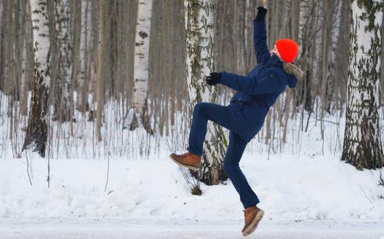 Mann rutscht auf Eis aus.