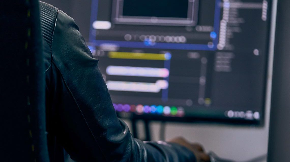 Person sitzt am PC und scheidet Filmsequenzen.