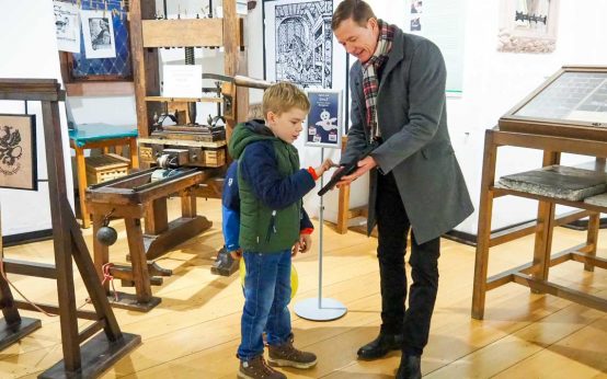 Eltville: Die kleinen Burggäste Silas und Matteo testen gemeinsam mit Thomas März, Geschäftsführer des Burgvereins, das Emil-Quiz in der Gutenbergausstellung