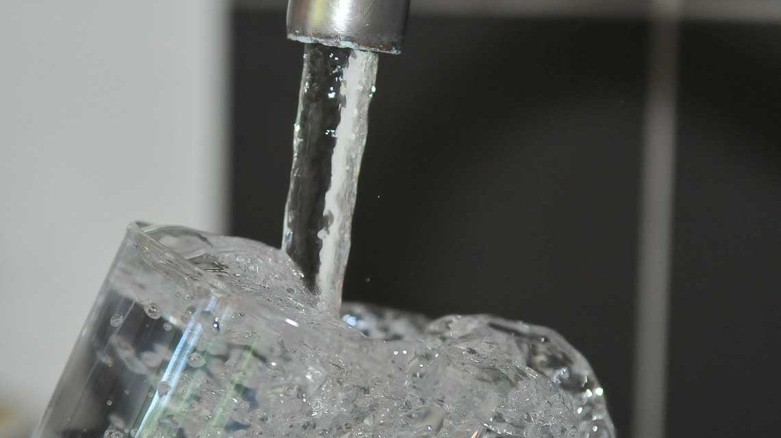 Wasserverbrauchssteuer: Trinkwasser aus Wasserhahn, Glas wird aufgefüllt.