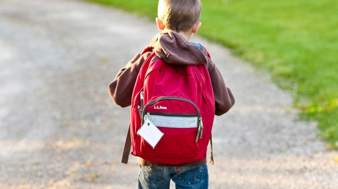 Erstklässler, Schulstart, Kleiner Junge mit Schulranzen auf dem Weg zur Schule.