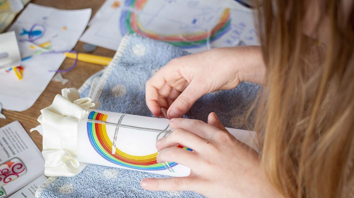 Kinderhände kleben ein buntes Bild zusammen. Symbolfoto fürs Kreativ-Labor.