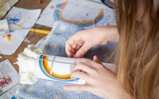 Kinderhände kleben ein buntes Bild zusammen. Symbolfoto fürs Kreativ-Labor.