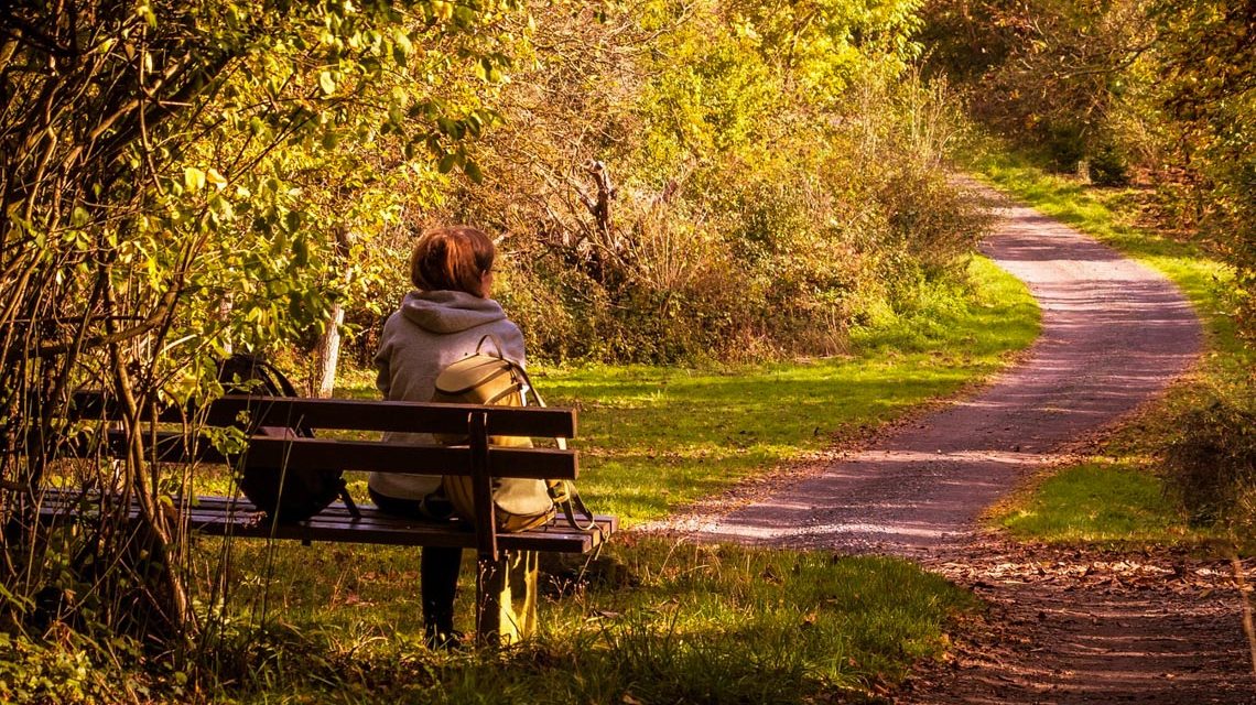 Tag des Wanderns. Frau sitzt auf Parkbank.
