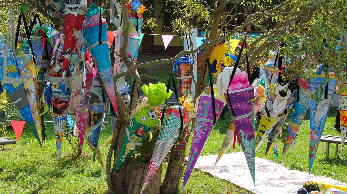 Symbolbild, viele bunte Schultüten hängen an einem Baum. Zum Schulanfang!