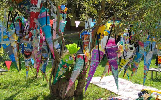 Symbolbild, viele bunte Schultüten hängen an einem Baum. Zum Schulanfang!