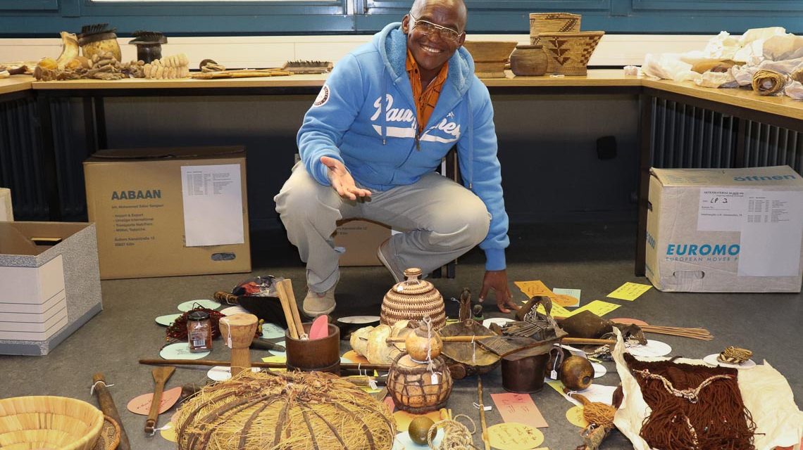 Der Vorsitzende des Bwabwata Khwe Custodian Committee, Sonner Geria begutachtet im Frankfurter Qswin Köhler Archiv wertvolle und selten gewordene Artefakte und Dokumente seiner Kultur. Foto: Oswin-Köhler Archiv, Frankfurt