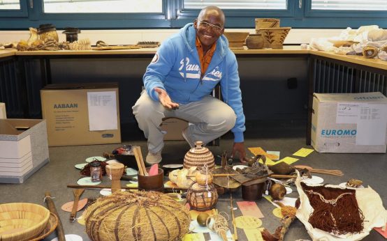 Der Vorsitzende des Bwabwata Khwe Custodian Committee, Sonner Geria begutachtet im Frankfurter Qswin Köhler Archiv wertvolle und selten gewordene Artefakte und Dokumente seiner Kultur. Foto: Oswin-Köhler Archiv, Frankfurt