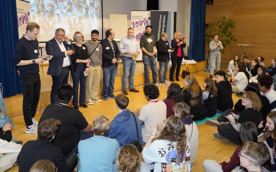 Oberbürgermeister Gert-Uwe Mende und Sozialdezernentin Dr. Patricia Becher auf der Wiesbadener Jugendkonferenz inmitten von Jugendlichen.