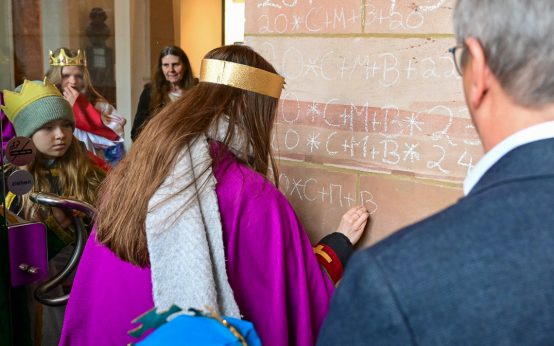 Sternsinger bringen Segen an der Pforte zum Rathaus an.