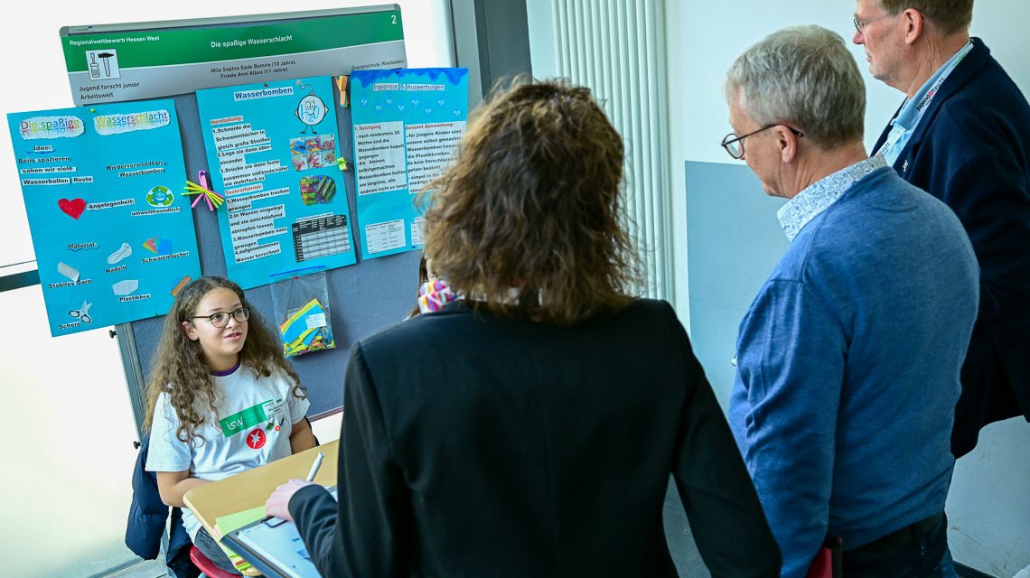 Jugend forscht, die Jury lässt sich die Wasserschlacht ohne Plastik erklären.