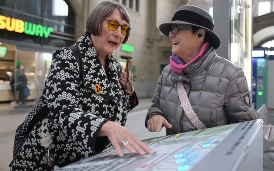 Barbara Knoblocj und Birgit Berg vom Arbeitskreis Inklusion und Barrierefreiheit Wiesbaden am Bedarfspult.