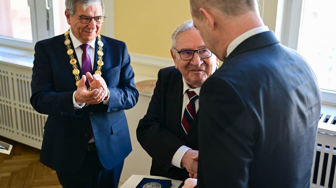 OB Gert-Uwe Mende steht im Hintergrund, Dr. Gerhard Obermayr gratuliert Bogdan Bartnikowski.