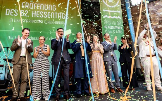 Bürgermeister Sebastian Wysocki, Staatskanzlei-Chef Benedikt Kuhn, Tanja Raab-Rhein, Ministerpräsident Boris Rhein, das Hessentagspaar Matthias Kallmeyer und Ena Kaufmann sowie Landrat Jan Weckler (v. l. n. r.) feiern die Eröffnung des Hessentages 2025 in Bad Vilbel.