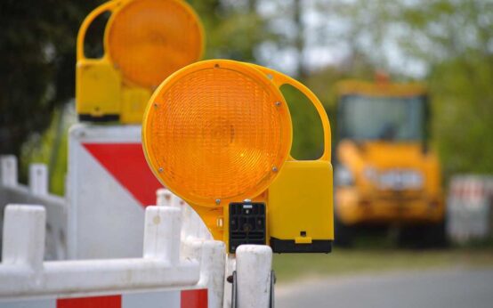 Baustellenabsperrung im Vordergrund, dahinter Baustellenfahrzeige in der Unschärfe.