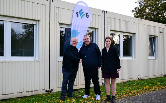 Andreas Guntrum gibt Mike Steinbach Hand und Schlüssel für die Container. Tanja Steinbach freut sich über das neue Vereinsheim für die Fauen-Mannschaften.