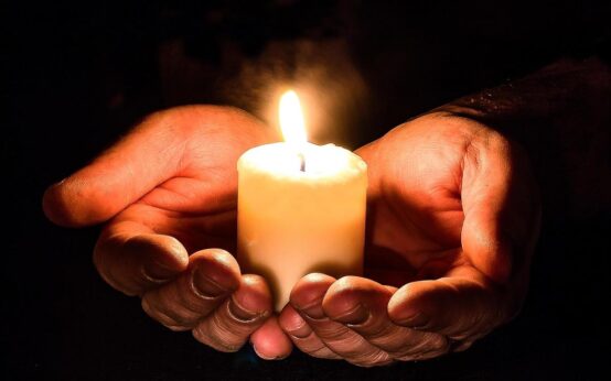 Symbolisches Bild, zwei Hände halten eine Kerze: das Friedenslicht.