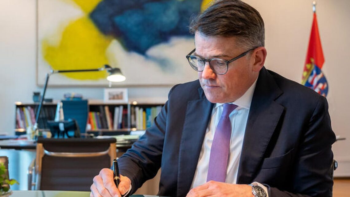 Ministerpräsident Boris Rhein unterschreibt Glückwunschkarten.