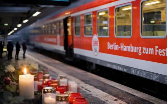 Gedenkkerze, Blumen am Bahngleis, Dahinter InterRegio-Zug.