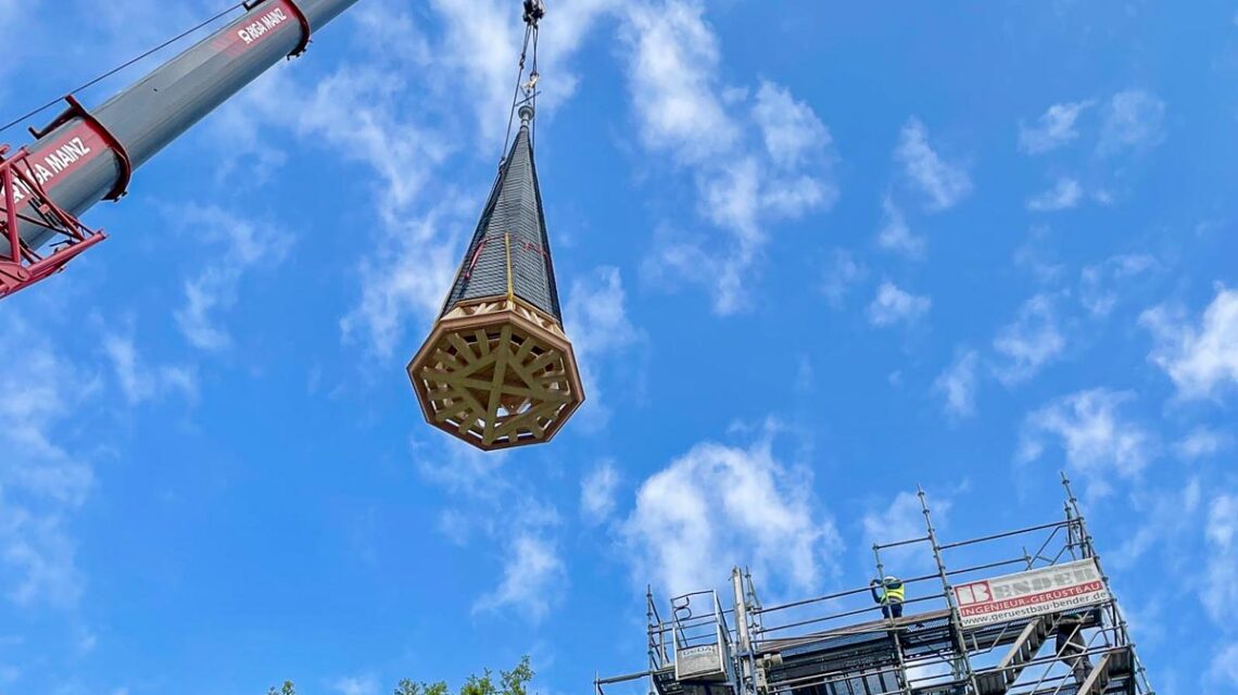 Ein Kran setzt die erneuerte Kirchturmspitze in Dotzheim millimetergenau auf das Dach der Evangelischen Kirche.