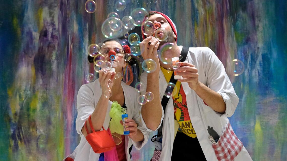 Zwei Clown mit roiter Nase pusten Seifenblasen.