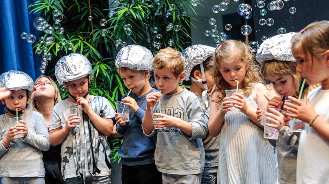 Eine Gruppe von Kindern die mit Strohhalm Luftblasen blubbern