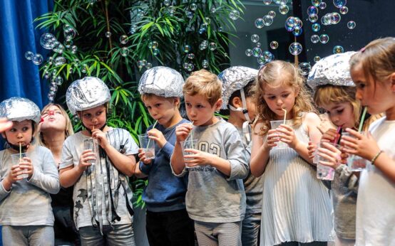 Eine Gruppe von Kindern die mit Strohhalm Luftblasen blubbern