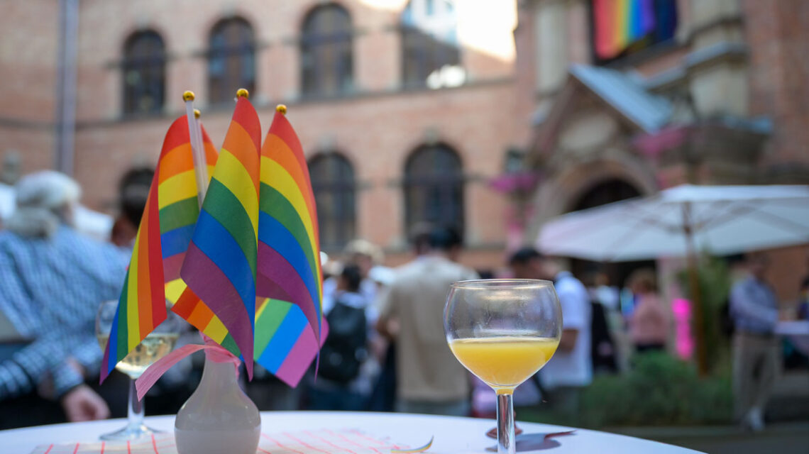 Das Bild zeigt einen Tisch mit kleinen Regenbogenfähnchen im Innenhof des Wiesbadener Rathauses.