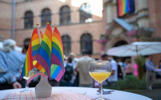Das Bild zeigt einen Tisch mit kleinen Regenbogenfähnchen im Innenhof des Wiesbadener Rathauses.